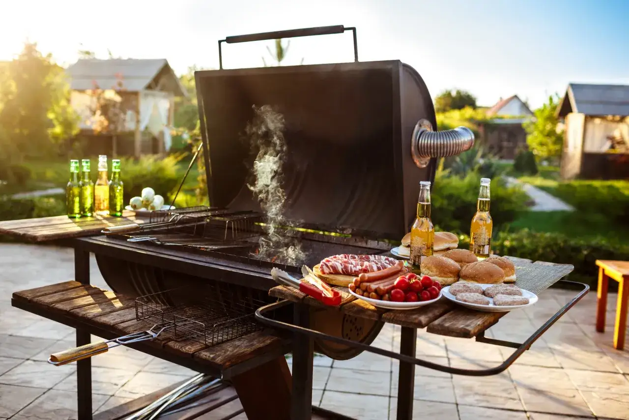 St&oacute;ł grillowy z r&oacute;żnorodnymi potrawami i ludźmi